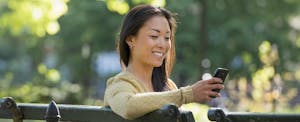 Smiling woman using Credit Karma Direct Dispute feature on her phone