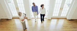 Mature realtor showing couple interior of house and explaining mortgage options