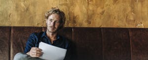 Man with bad credit, seeking a loan and sitting on couch in unfinished room