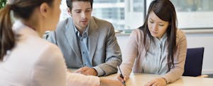Couple going over documents with person behind desk