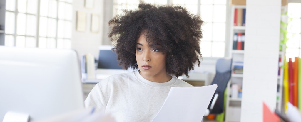 Serious woman sitting at desk and using computer