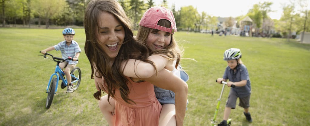 Young smiling mother playing outside with her three kids