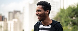 Man standing outside in a city, smiling as he reads on his phone about the best personal loans with no origination fee