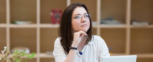Woman considering options with laptop open.