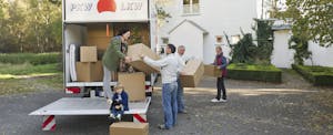 People unloading moving truck in driveway