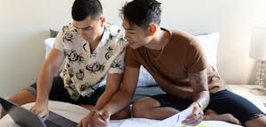 Couple sitting together with a laptop, looking over documents
