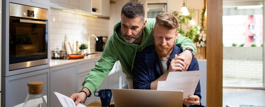 Loving gay couple in front of paperwork on their kitchen table, wondering if HELOC interest is tax deductible