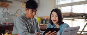 Couple sitting in their kitchen, reviewing their finances as they decide between a home equity loan and a personal loan